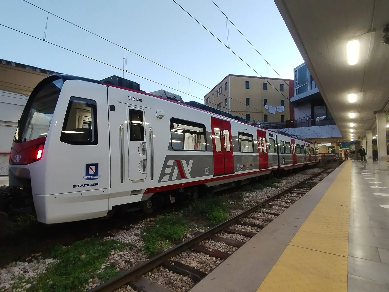 Treno ETR 300 bianco e rosso della Circumvesuviana EAV fermo lungo la banchina di una stazione